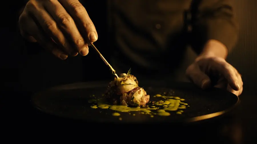 Manos del cocinero terminando un platillo con salsa verde